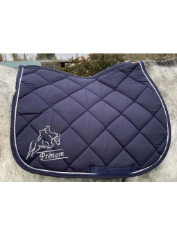 tapis de selle bleu marine personnalisé avec prénom brodé il cheval qui saute au dessus de l'obstacle